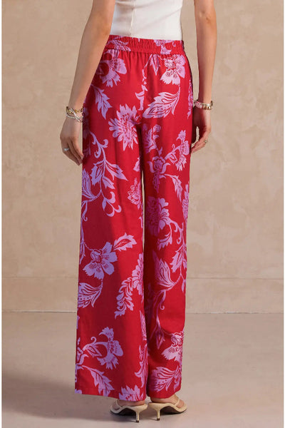 Red wide leg pants with oversized lavender and pink floral digital print, elastic self-tie drawstring waist and side pockets, back view