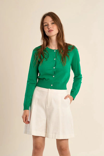 Emerald green slim-fit knitted cardigan with heart button closure and white shorts - front view.