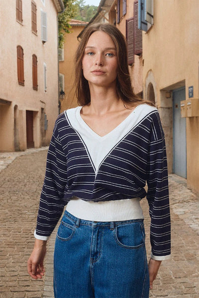 Navy and white striped V-neck knit sweater with long sleeves and white contrast trim - outdoor lifestyle front view.