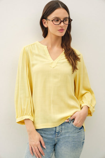 Yellow notched Y-neck volume sleeve top with ruffle cuffs and relaxed fit paired with jeans