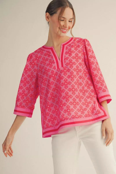 Model wearing 3/4 Sleeve Medallion Pattern Top with contrast detail - front view showing hot pink medallion print, V-notch neckline, and striped trim.