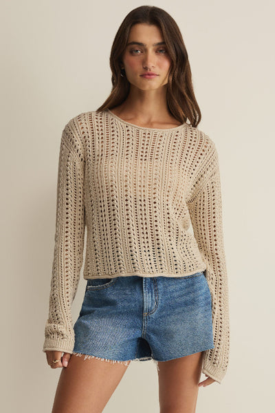 Island Coconut beige open-knit crochet crew neck sweater with long sleeves, styled with denim shorts, front view.