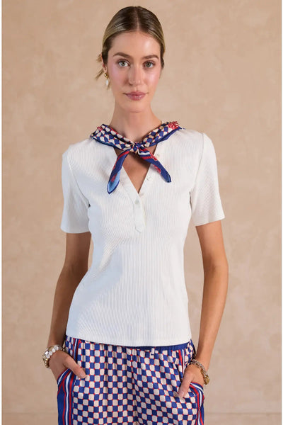 White fitted ribbed knit top with V-neck woven placket and geo checkerboard navy and red printed scarf tied at neck, front view.