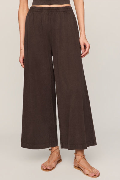 Z Supply Scout Jersey Crop Flare Pant in dark chocolate, wide-leg silhouette, elastic waistband, mineral wash cotton, cropped length — front view styled with strappy sandals.