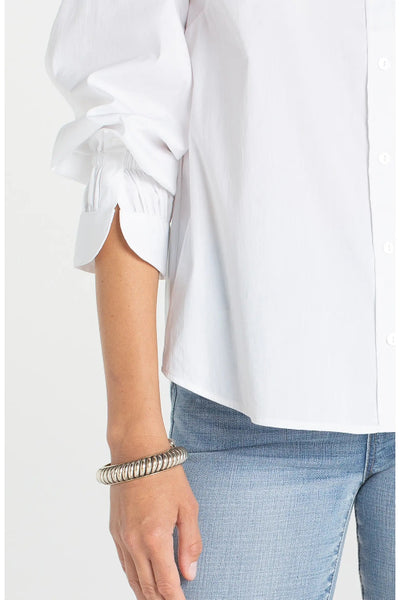 Close-up detail of scrunched adjustable sleeve cuff on white Liverpool woven button front top, with silver bangle bracelet.