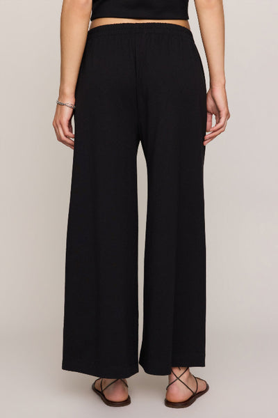 Z Supply Scout Jersey Crop Flare Pant in black - back view, high-rise elastic waistband, wide-leg silhouette, 100% cotton jersey.

