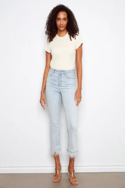 Charlie b light wash stretch denim flare pants with removable feather trim hem detail, styled with strappy heeled sandals, front view.