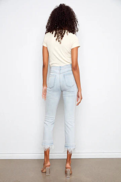 Charlie b light wash stretch denim flare pants with removable feather trim hem detail, styled with strappy heeled sandals, back view.