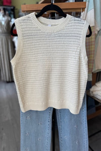 Ivory sleeveless textured sweater vest with waffle-knit pattern.