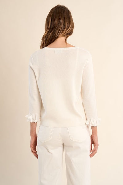 Back view of off-white fancy cardigan showing clean lines and ruffle sleeve details, styled with white trousers.