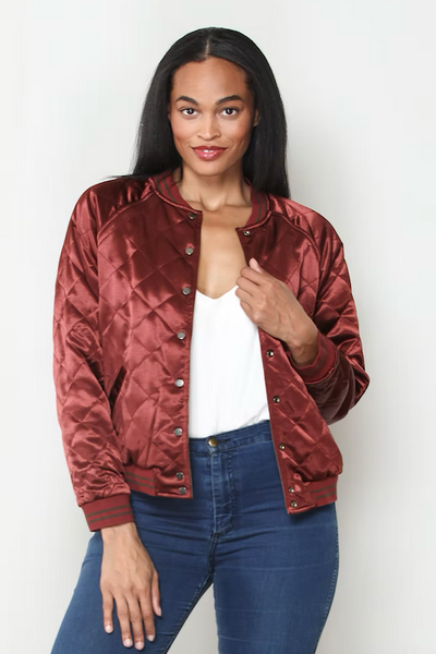 Front view of model wearing burgundy quilted satin side of reversible bomber jacket;reversible satin bomber jacket women; burgundy quilted bomber jacket; olive satin bomber jacket; floral embroidered bomber jacket; Paparazzi reversible jacket; women’s burgundy satin jacket; olive floral jacket women; lightweight reversible bomber jacket; vintage-inspired floral bomber jacket.