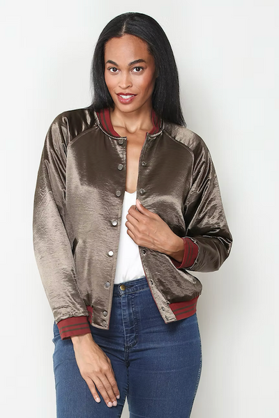 Front view of model wearing olive satin side of reversible bomber jacket with burgundy ribbed trim;reversible satin bomber jacket women; burgundy quilted bomber jacket; olive satin bomber jacket; floral embroidered bomber jacket; Paparazzi reversible jacket; women’s burgundy satin jacket; olive floral jacket women; lightweight reversible bomber jacket; vintage-inspired floral bomber jacket.
