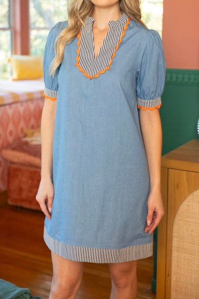 Light blue chambray shift dress with navy striped trim and orange ric rac detail, front view showing v-neckline and puff sleeves
