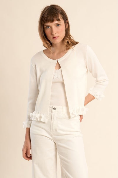 Off-white open-front cardigan with ruffle cuffs over white pants, front view showing elegant drape and feminine details.