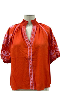 Orange blouse with pink embroidered sleeves and V-neckline.