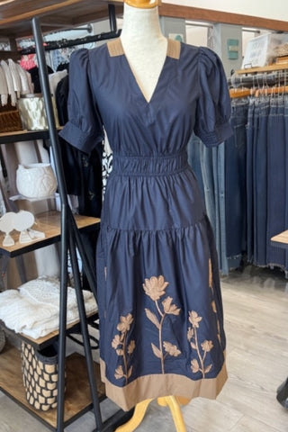 Navy midi dress with tan floral embroidery, puff sleeves, and a cinched waist.