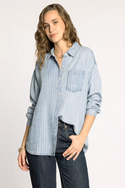 Helena Shirt in multi pinstripe blue and white pattern, relaxed fit button-down with dropped shoulders and chest pocket, styled with dark denim jeans.