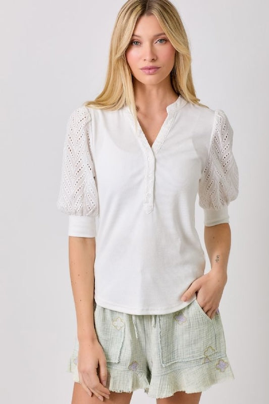 Ribbed knit top with chevron eyelet puff sleeves and v-neck button detail.