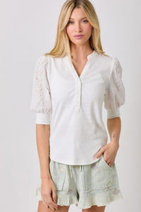 Ribbed knit top with chevron eyelet puff sleeves and v-neck button detail.