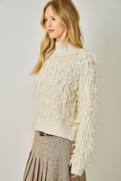 Side view of the Mystree ivory shaggy knit mock neck sweater showing its textured knit and ribbed hem.Mystree ivory sweater; Mystree shaggy knit sweater; ivory mock neck sweater; women's shaggy pullover sweater; textured ivory sweater; long sleeve mock neck sweater; ivory fall sweater for women; women's neutral winter sweater; Mystree 61640 sweater; ivory sweater with ribbed hem