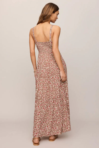 Model is wearing a floral dress with flat sandals, back view. 