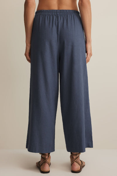 Vintage indigo wide-leg cropped linen blend pants with elastic waistband, styled with strappy sandals, back view.