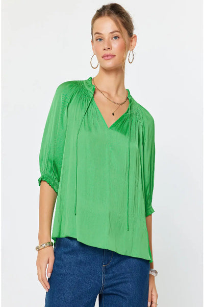 Angelica Kelly green pleated pullover top with V-neck tie detail, ruffle-trimmed neckline, and elasticized ruffle cuffs, front view.