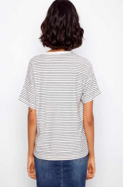 Back view of Woman wearing a striped embroidered shirt and denim skirt.