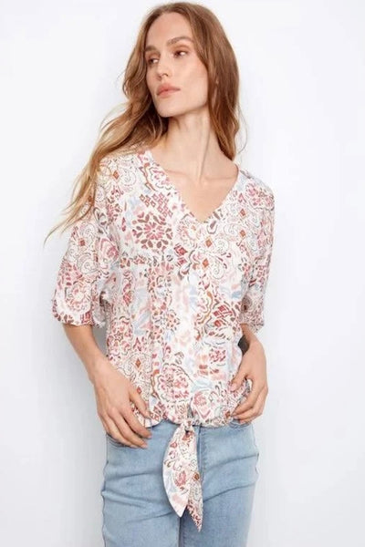 Charlie b ivory printed dolman sleeve popover blouse with self-tie front, styled with denim jeans, front view.