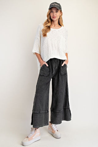Wide-leg mineral washed black cotton palazzo pants with raw edge seams and front patch pockets.