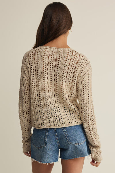 Island Coconut beige open-knit crochet crew neck sweater with long sleeves, styled with denim shorts, back view.