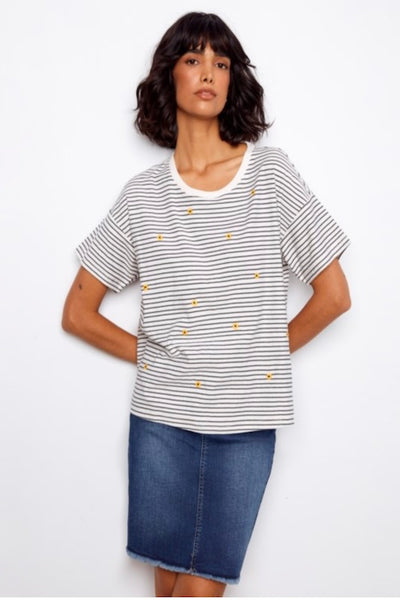 Woman wearing a striped embroidered shirt and denim skirt.