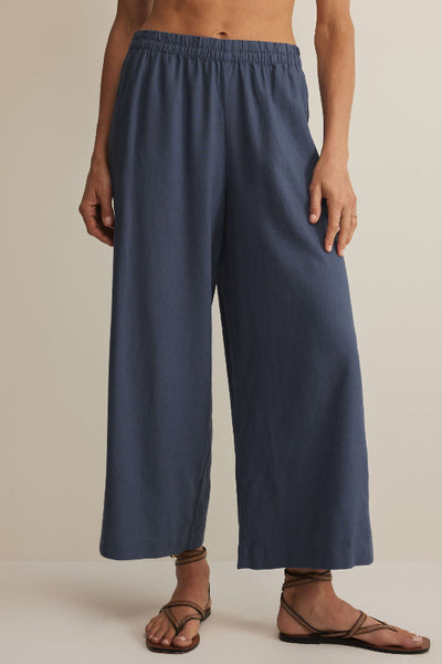 Vintage indigo wide-leg cropped linen blend pants with elastic waistband, styled with strappy sandals, front view.