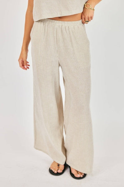 Garden Sun Pants in neutral ribbed fabric with wide-leg silhouette, front view showing elastic waistband and full-length hem with black sandals.