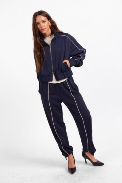 Model wearing Sage the Label Bike Ride navy joggers with matching track jacket;Sage the Label Bike Ride Joggers
Sage the Label navy joggers
women’s navy and ivory joggers
navy joggers with ivory piping
women’s tapered jogger pants
women’s pull-on track pants
women’s matching track set
lined polyester joggers for women
sporty chic navy pants
relaxed-fit ankle joggers