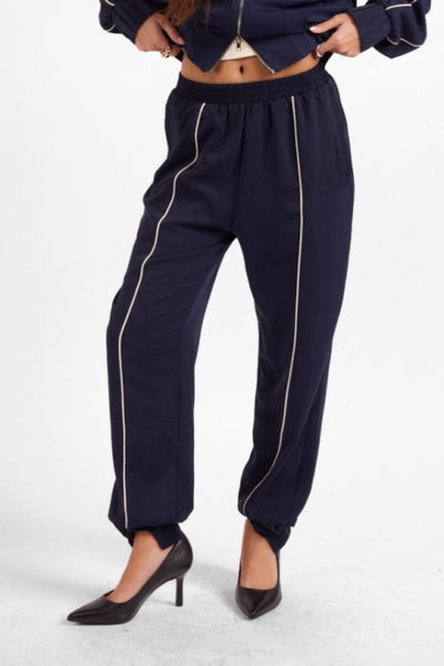 Front view of Sage the Label Bike Ride navy joggers with ivory piping;Sage the Label Bike Ride Joggers
Sage the Label navy joggers
women’s navy and ivory joggers
navy joggers with ivory piping
women’s tapered jogger pants
women’s pull-on track pants
women’s matching track set
lined polyester joggers for women
sporty chic navy pants
relaxed-fit ankle joggers