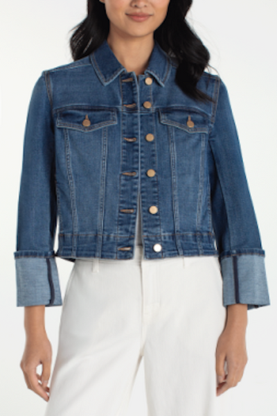 Medium blue cropped denim trucker jacket with wide cuffed bracelet-length sleeves and button-front closure, styled with white pants.